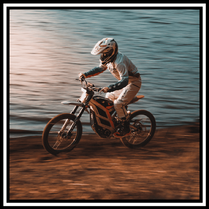 Rider maneuvering the 🇮🇪🇪🇺🇬🇧🇺🇸 79BIKE-FALCON PRO 10000W OFF-ROAD electric dirt bike near a water body.