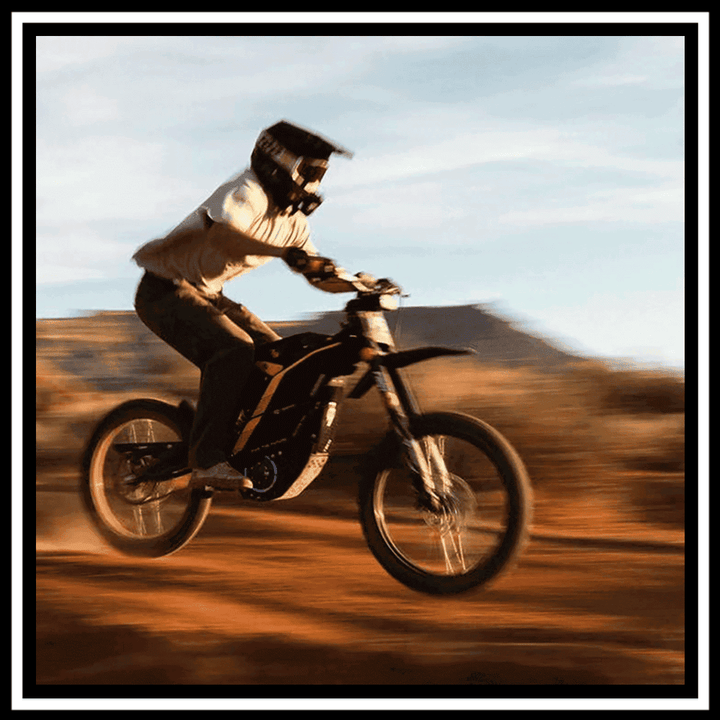 A rider on the 🇮🇪🇪🇺🇬🇧🇺🇸 79BIKE-FALCON PRO 10000W OFF-ROAD electric dirt bike performing a jump.