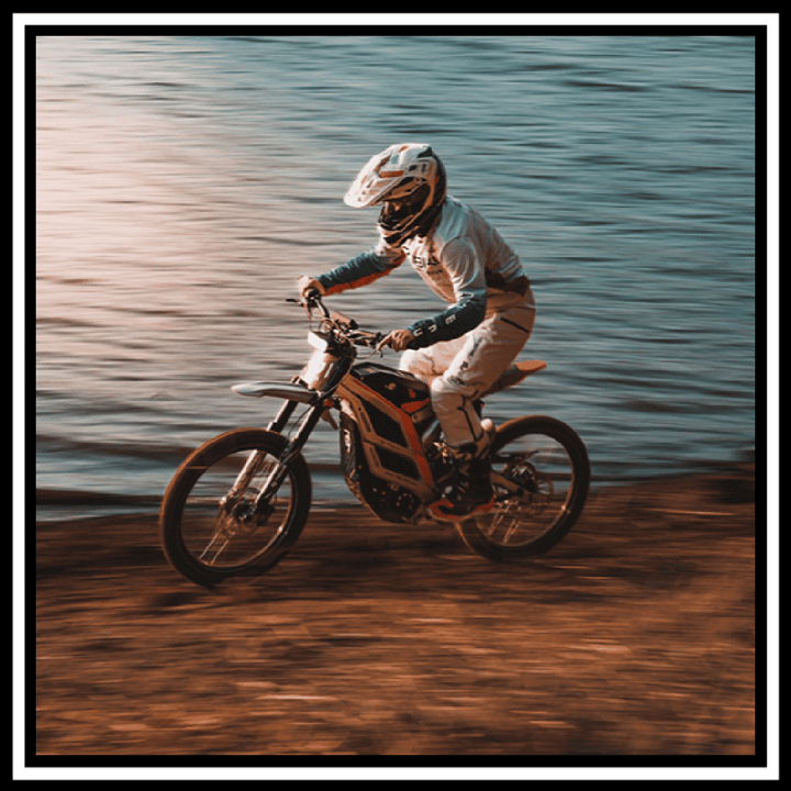 Person riding the 79BIKE-FALCON PRO ELECTRIC DIRT BIKE near a river, showcasing its performance and features.