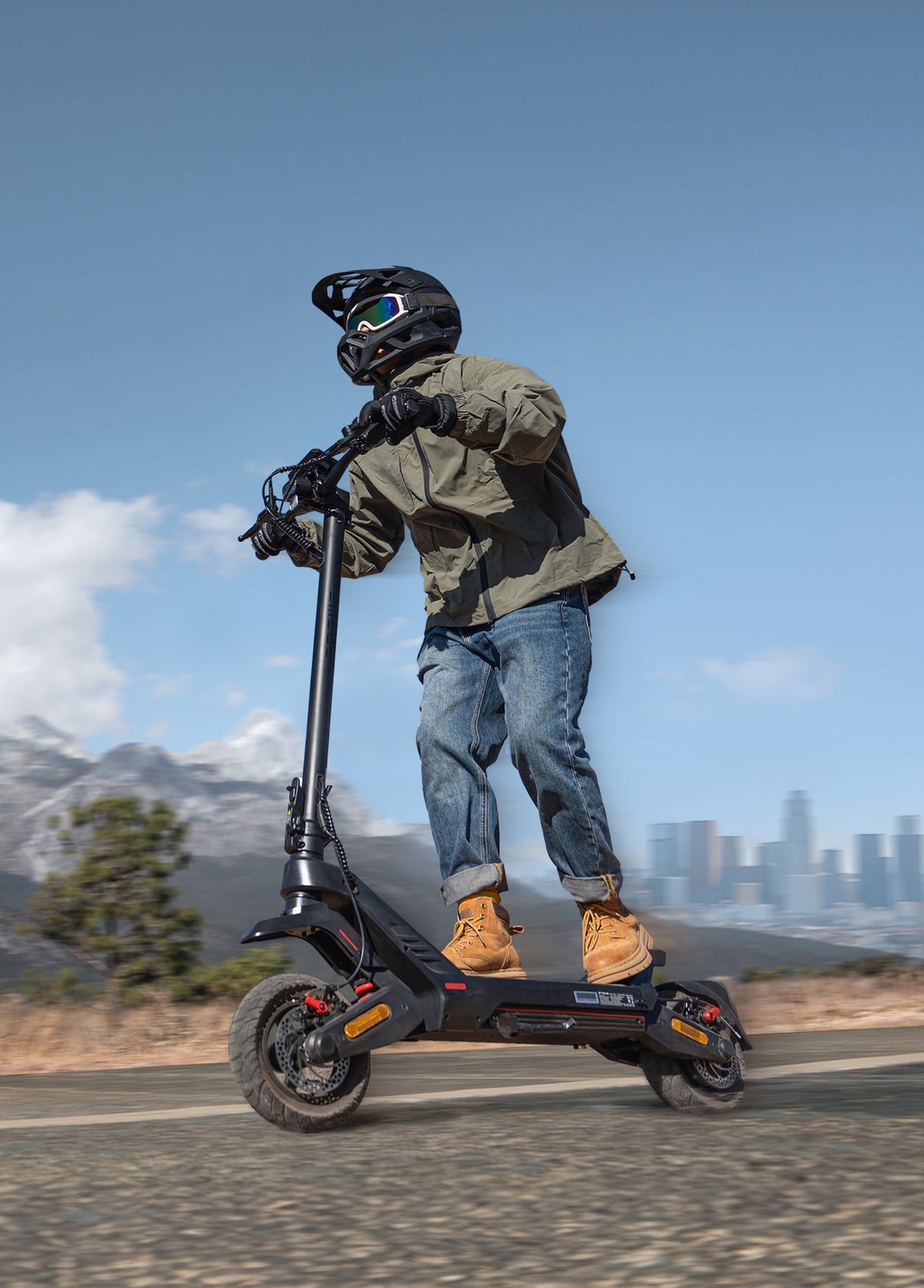 Person riding an electric scooter on a scenic road with mountains and city skyline in the background.