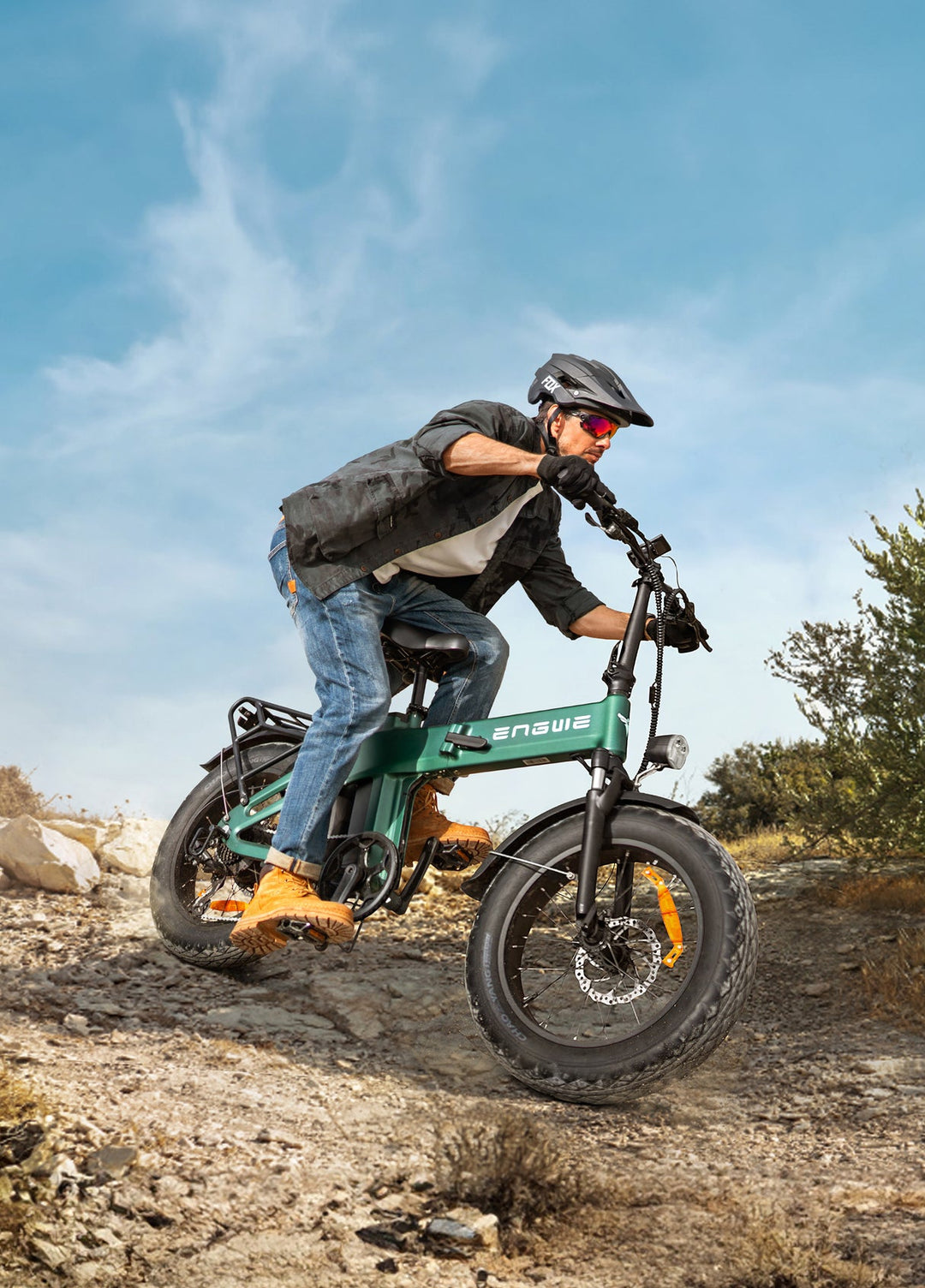 Rider navigating rocky terrain on a green electric bike, showcasing off-road capabilities under a blue sky.