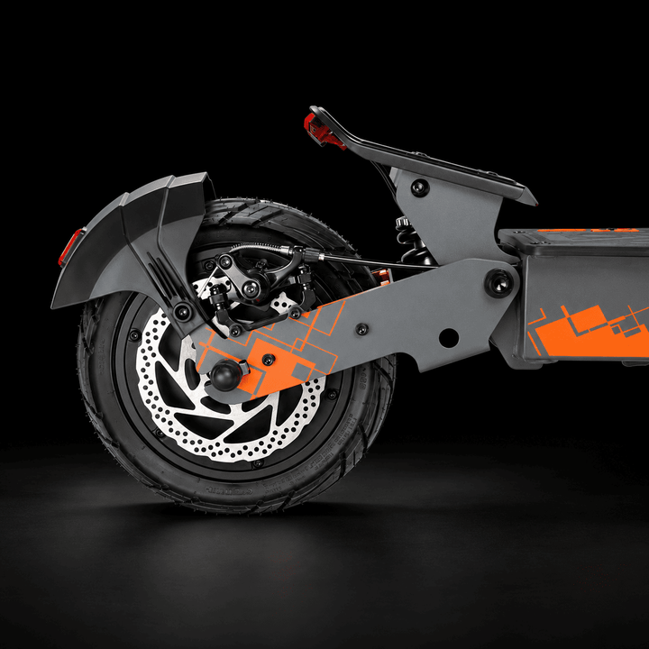 Kukirin G4 Ultra Electric Scooter - Close-up rear three-quarter view of a modern electric scooter with a dark gray frame, black tire, silver brake disc, and bright orange graphic accents on a black studio background.