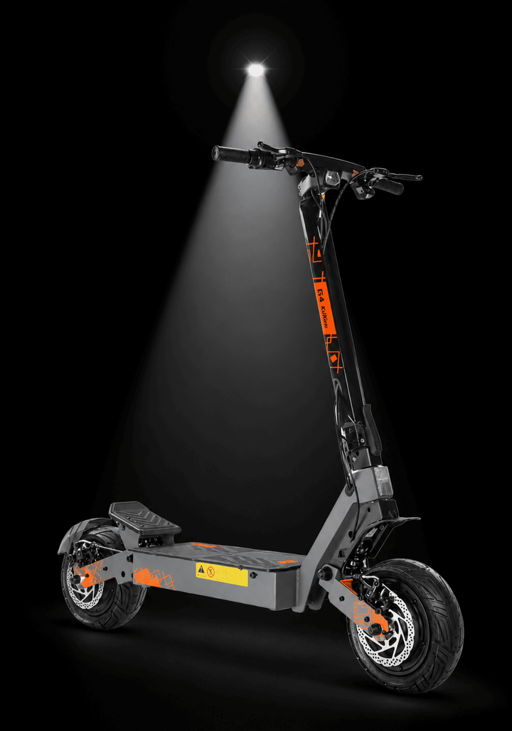Kukirin G4 Ultra Electric Scooter - A foldable electric scooter with a dark gray frame and bright orange accents, shown on a black background with a spotlight effect shining down on it.