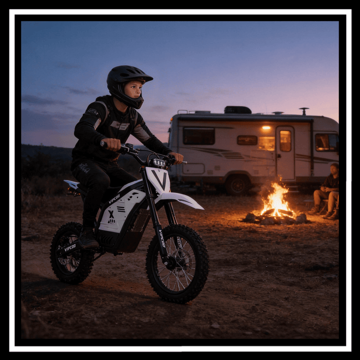 A rider on a VIPCOO H2 electric dirt bike near a campfire and RV at dusk.