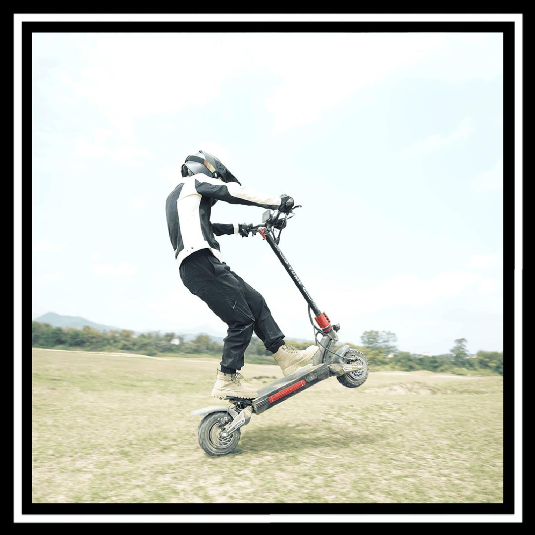 Rider performing a stunt on a YUME Raptor 2 electric scooter in an outdoor setting.