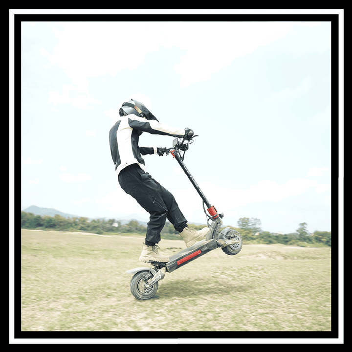 Rider performing a stunt on a YUME Raptor 2 electric scooter in an outdoor setting.