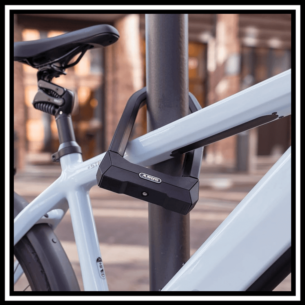 ABUS GRANIT X-PLUS SAFER LOCKER ELECTRIC BIKE LOCK secured to a bike frame against a post.