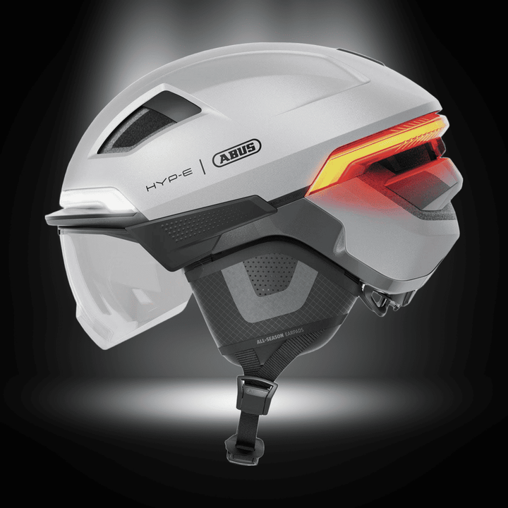 ABUS HYP-E ACE BICYCLE HELMET showing side view with integrated lights and visor for urban commuting safety.