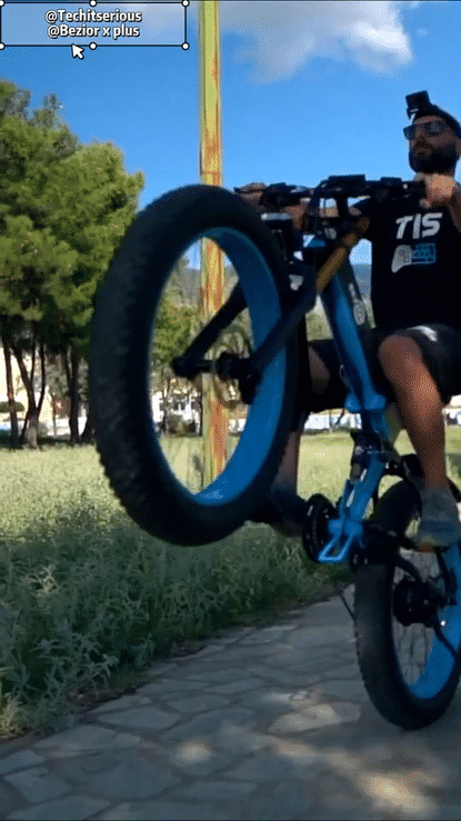 🇮🇪🇪🇺 BEZIOR X PLUS 1500W rider performing a wheelie on a blue electric mountain bike in a park.