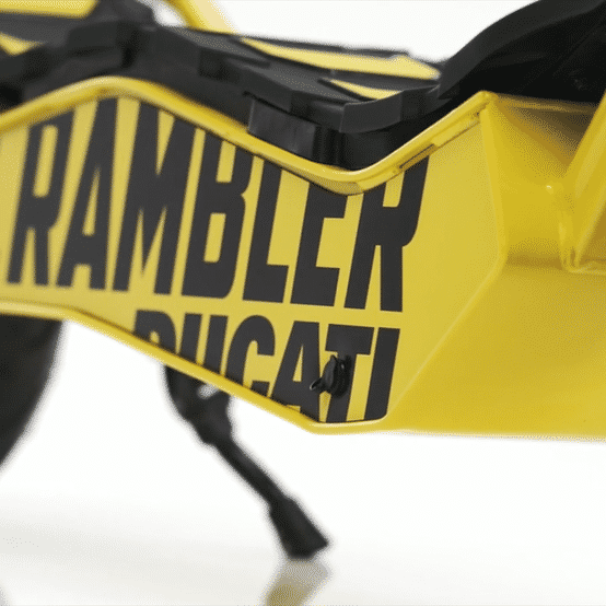 Ducati Scrambler E-Cross scooter close-up view showcasing the bold RAMBLER and DUCATI branding on the yellow frame.
