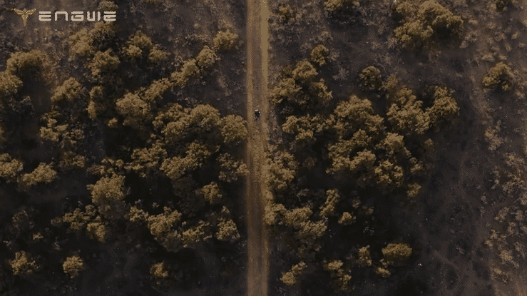 Aerial view of a rider using the ENGWE Y1000 Electric Scooter on a dirt path surrounded by trees.