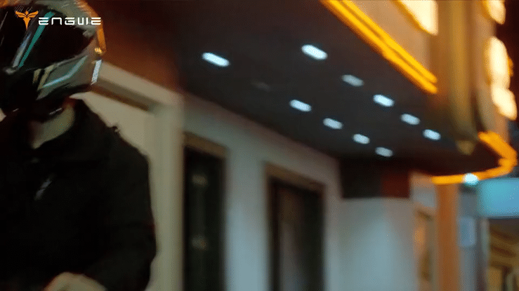 Person riding ENGWE Y400 electric scooter at night with urban lights in background.