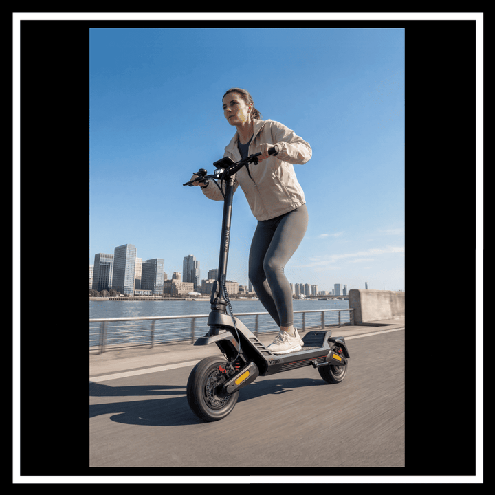 Woman riding ENGWE Y700 Electric Scooter on a city street with skyline in the background.