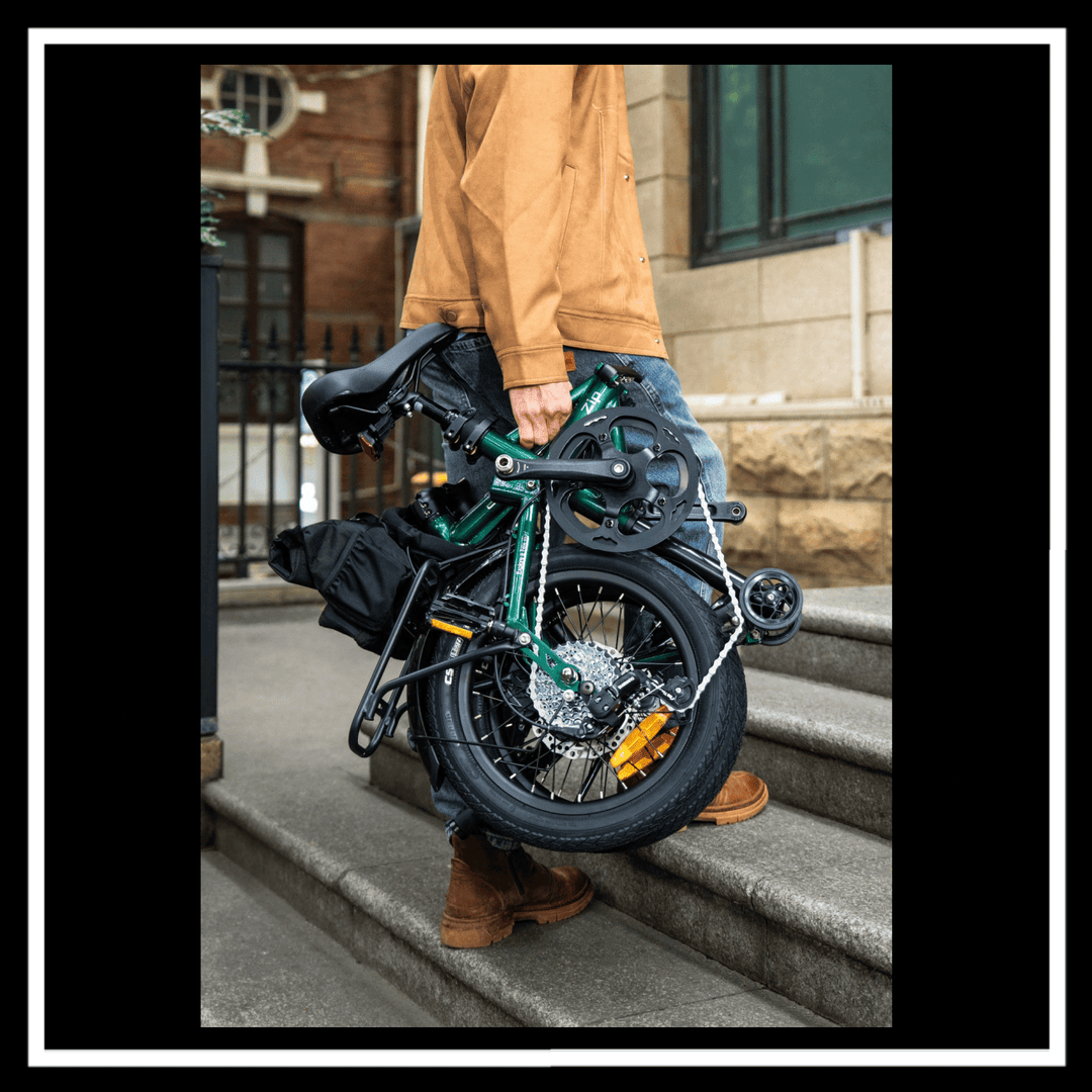 Person carrying the ENGWE ZIP ELECTRIC BIKE up a flight of stairs in a city setting.