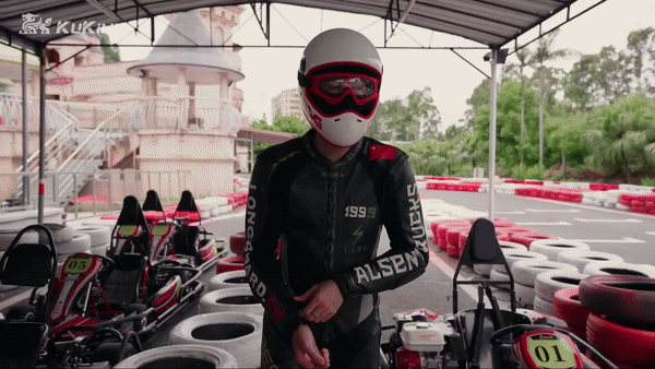 Rider in racing gear preparing for a kart race at an outdoor go-kart track.