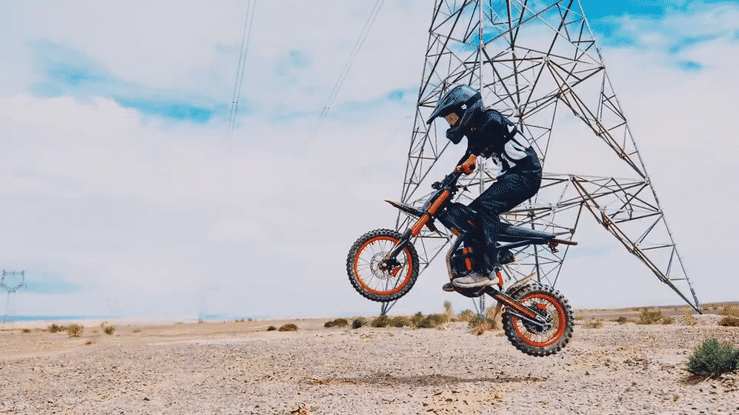 A rider in protective gear jumps on the 🇮🇪🇪🇺🇺🇸 GT54 2000W RIDING'TIMES ELECTRIC MINI E-BIKE in a desert landscape.
