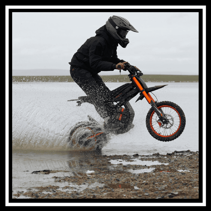 GT54 2000W RIDING'TIMES ELECTRIC MINI E-BIKE rider performing a splash jump on wet terrain.