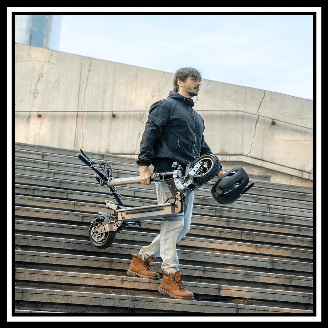 Man carrying the 🇮🇪🇪🇺🇬🇧🇺🇸 iENYRID S1 electric scooter down the stairs, showcasing its foldable design.