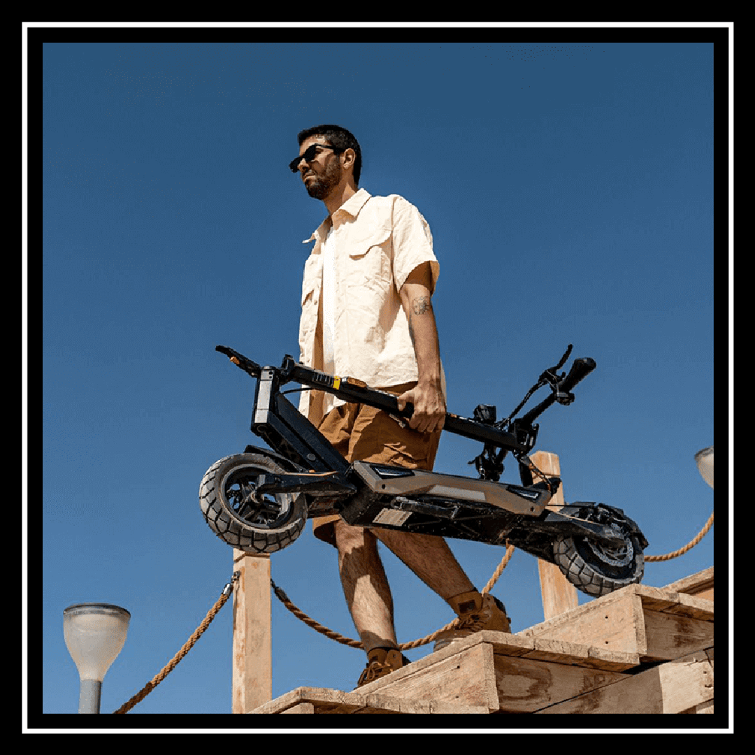 Man holding a kukirin electric scooter t3 while walking up stairs under a clear blue sky.