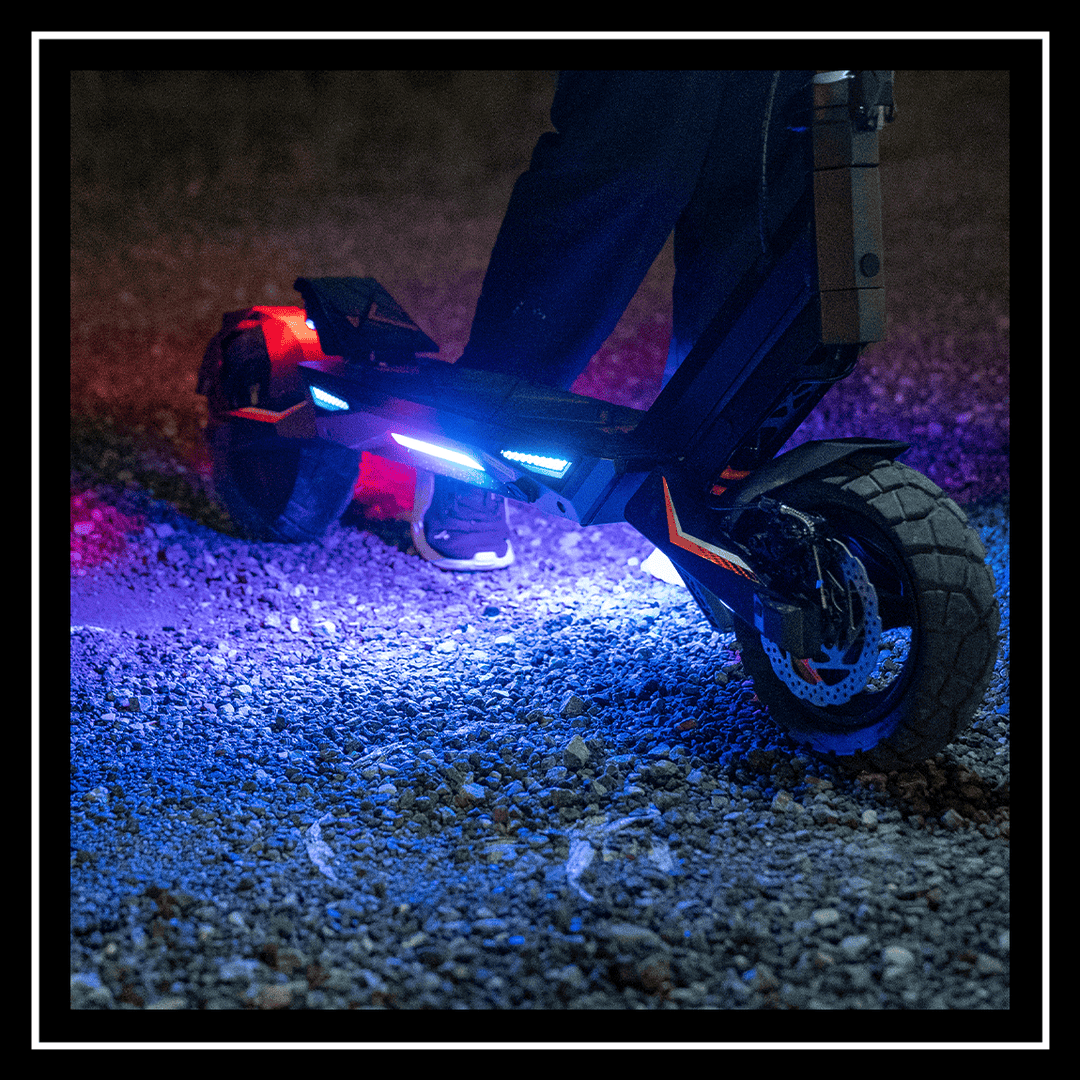 Close-up of the 🇮🇪🇪🇺 KUKIRIN T3 ELECTRIC SCOOTER with colorful lights illuminated on gravel.