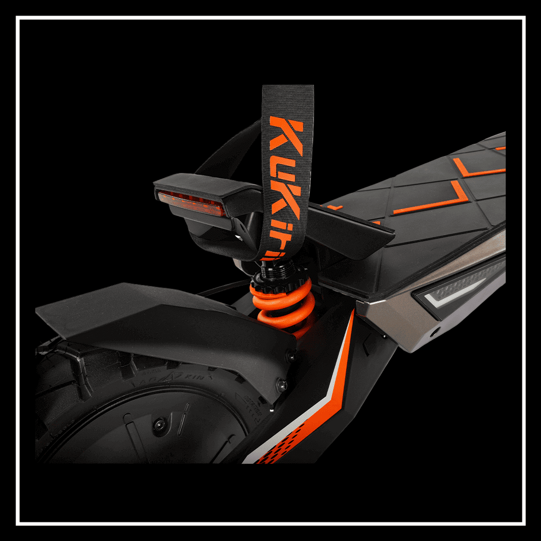 Close-up of the rear suspension and design details of the KuKirin T3 electric scooter featuring vibrant orange accents.