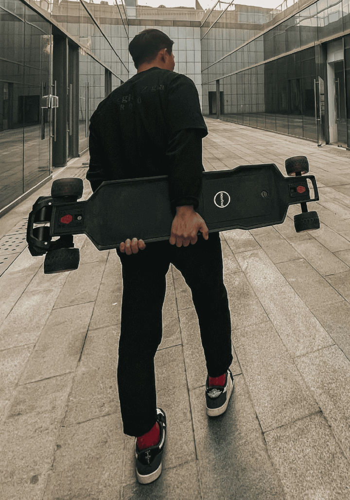 Person carrying MAXFIND FF BELT belt-driven electric skateboard in an urban setting.