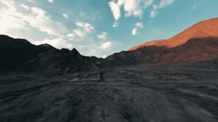 A person riding the 🇮🇪🇪🇺 KUKIRIN G2 ULTRA electric scooter on a rocky landscape under a blue sky.