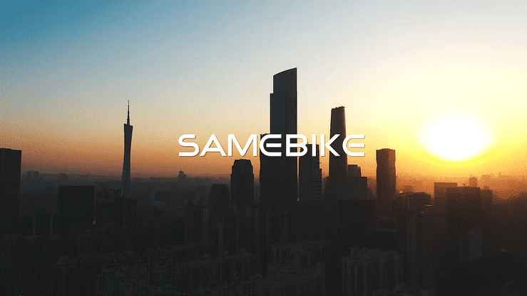 Aerial view of a city skyline at sunrise with the SAMEBIKE logo prominently displayed.