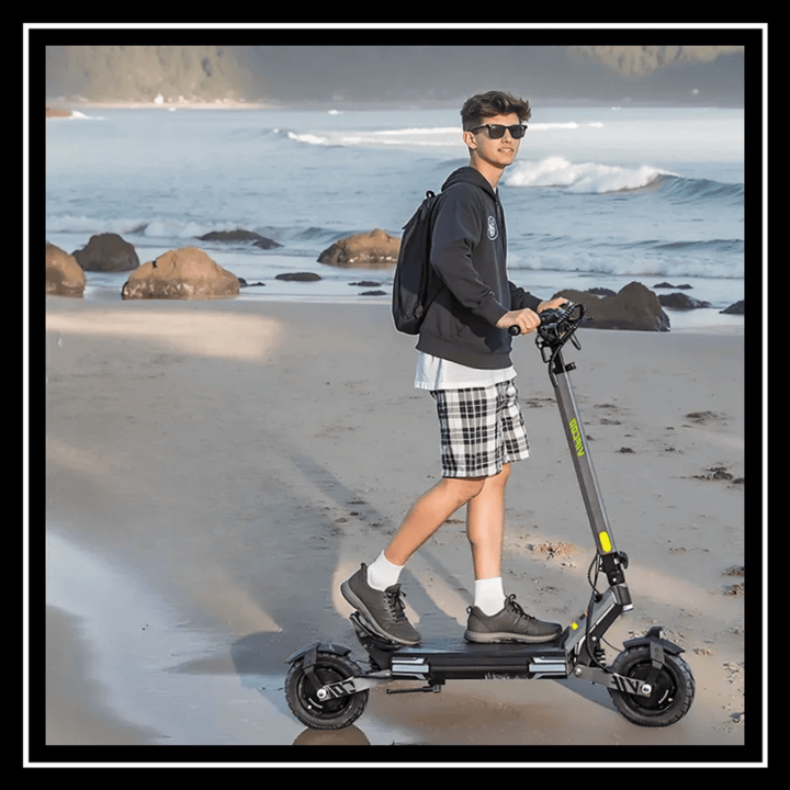 Person riding VIPCOO VS6 ELECTRIC SCOOTER on a beach with ocean waves in the background.