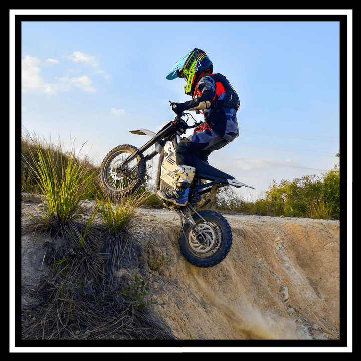 Rider performing a jump on a VIPCOO H2 electric dirt bike against a blue sky.