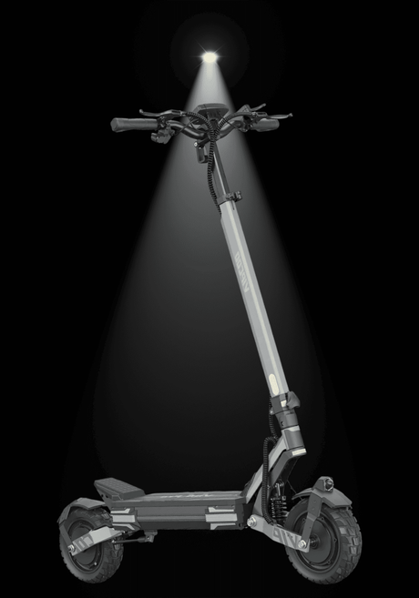 Modern electric scooter illuminated by a spotlight against a dark background, showcasing its sleek design and rugged tires.