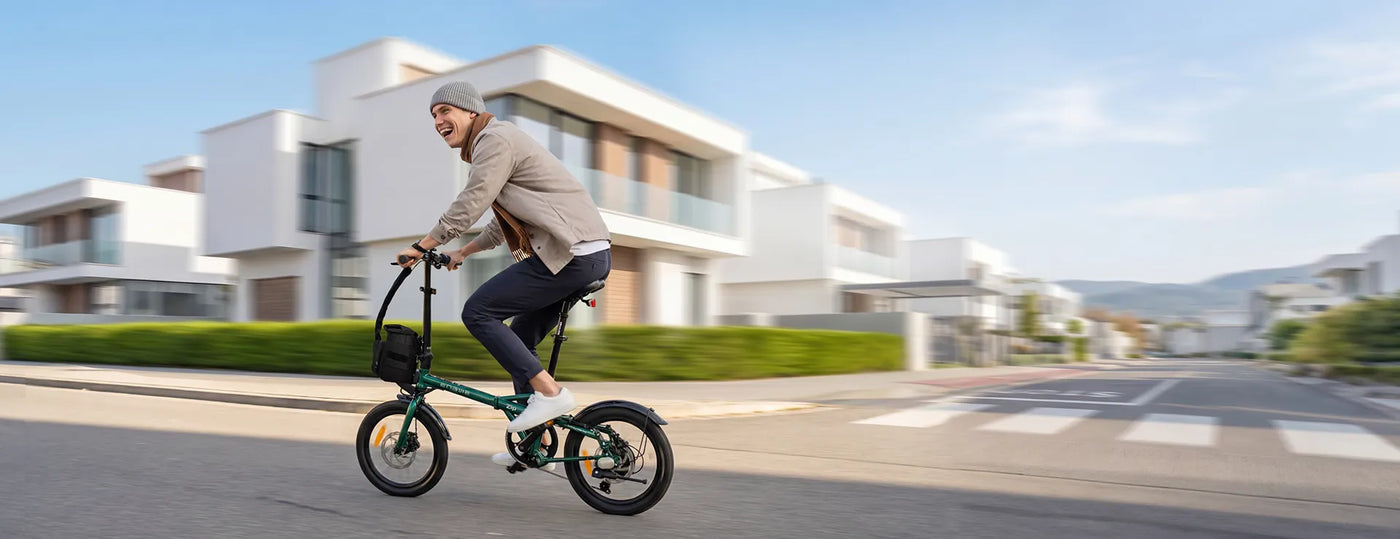 Man riding a compact bike on a sunny street with modern homes, showcasing urban cycling.