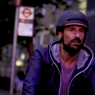 A man wearing a BH51M NEO URBAN smart urban bike helmet while biking in a city at night.