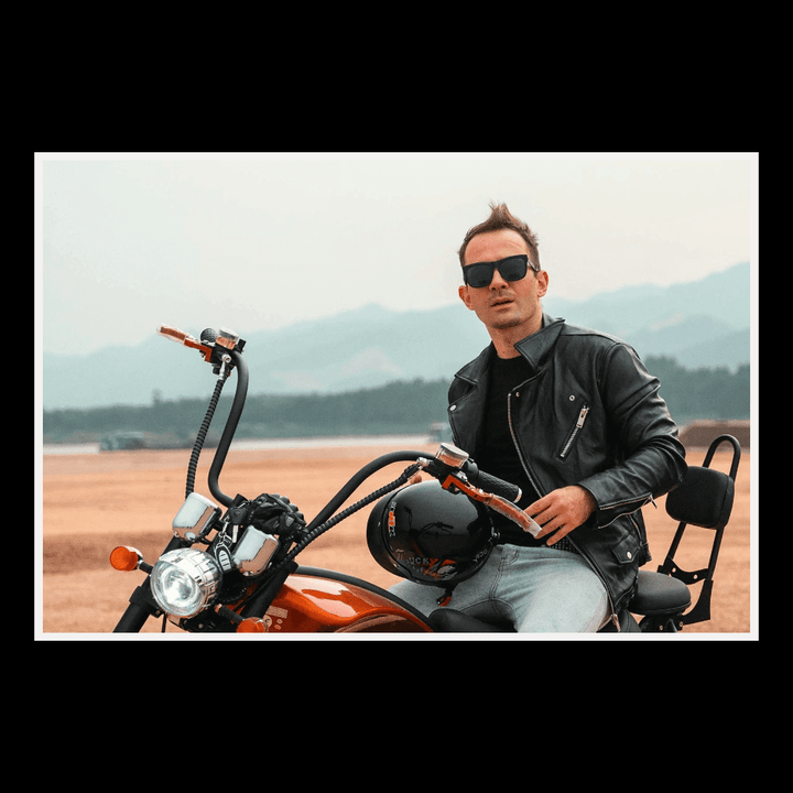EAHORA MP1 two-seat electric motorcycle with rider in leather jacket and sunglasses on outdoor terrain.