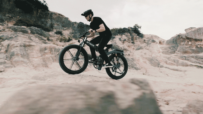 Rider performing a jump on the Engwe X26 electric bike over rocky terrain.
