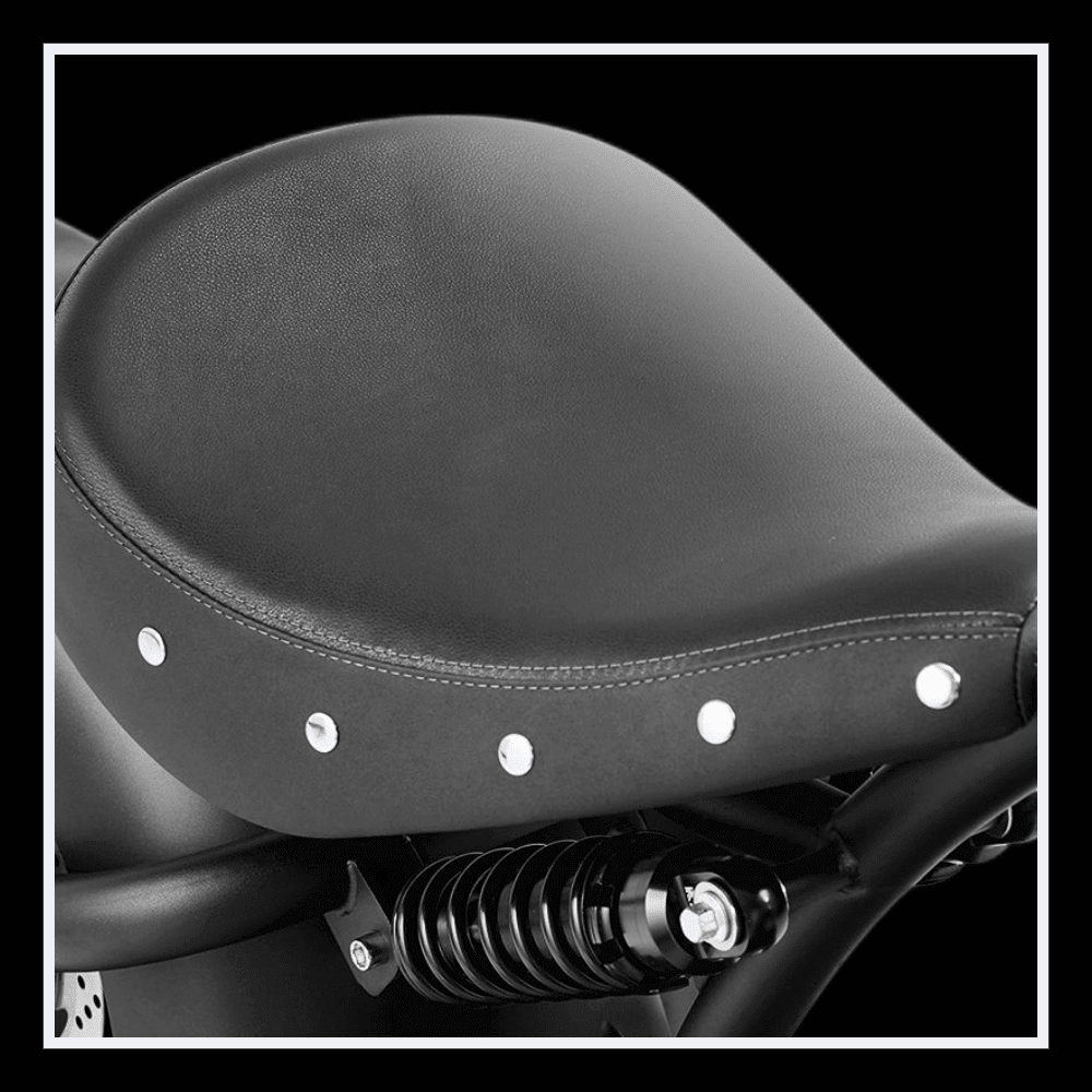Detailed view of the black seat of the INTHEZONE M1PS electric motorcycle showing chrome studs and suspension.
