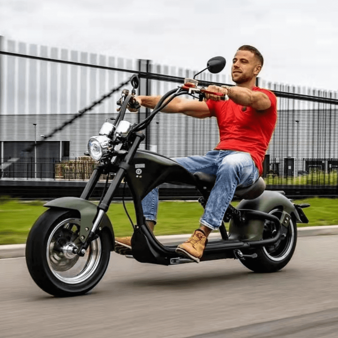 M1P electric chopper motorcycle riding on a road featuring a rider in a red shirt and casual wear.