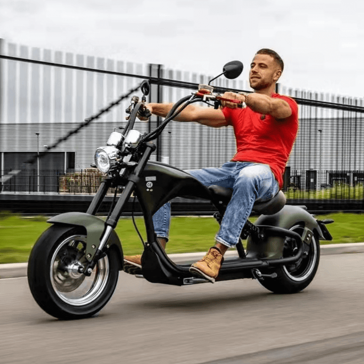 M1P electric chopper motorcycle riding on a road featuring a rider in a red shirt and casual wear.