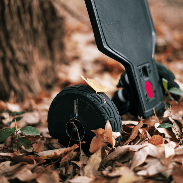 Maxfind FF AT electric skateboard wheel resting on colorful autumn leaves.