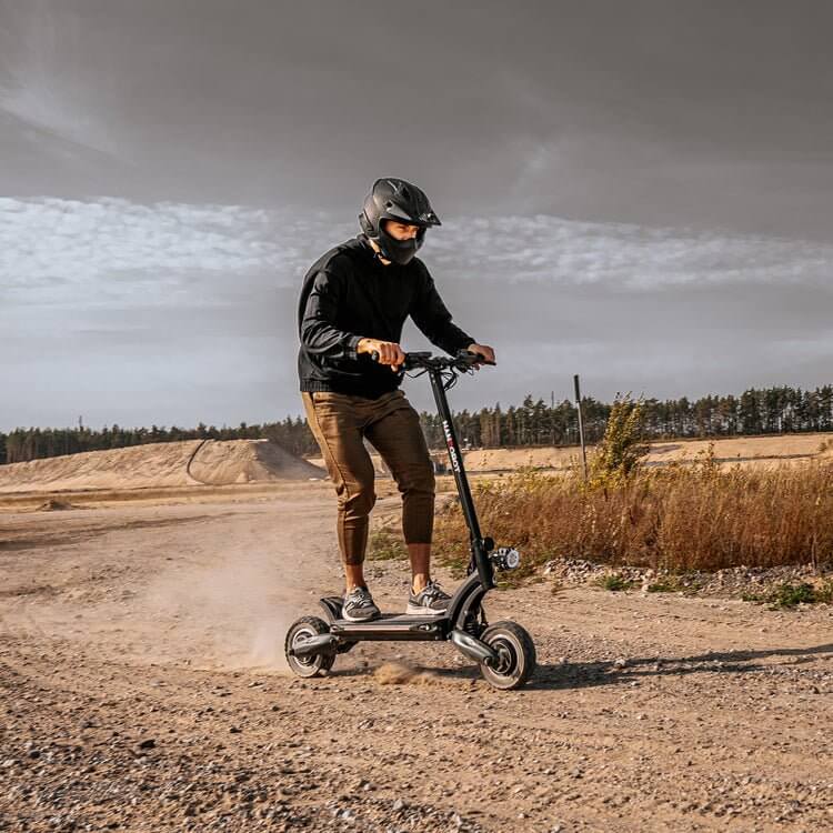 Person riding the Nanrobot D6+ electric scooter on a dirt path, showcasing its off-road capabilities.