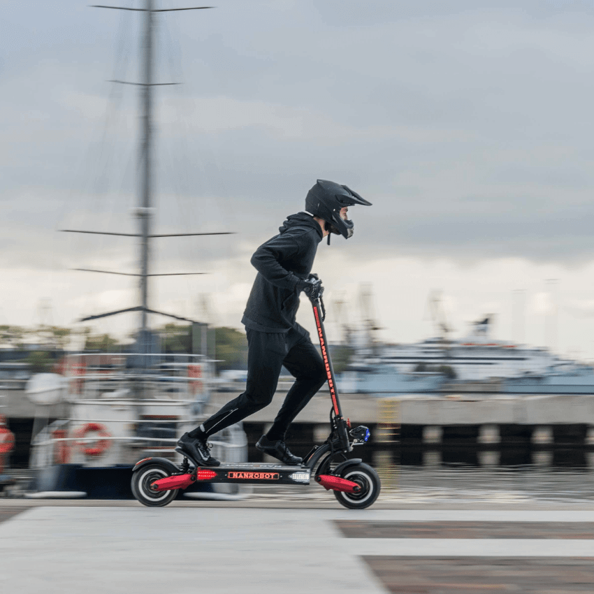 Person riding the Nanrobot LS7+ electric scooter at a harbor, showcasing its speed and dual-motor performance.