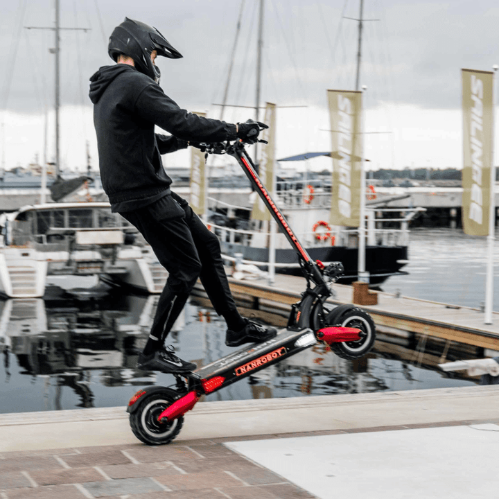 A rider performing tricks on the Nanrobot LS7+ electric scooter by the waterfront.