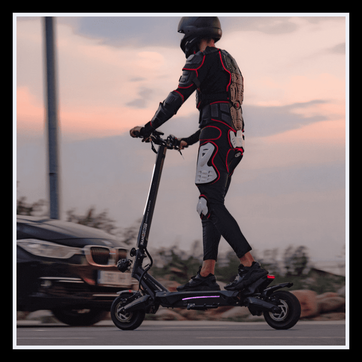Rider on NANROBOT N6 electric scooter wearing protective gear, cruising on a city street at sunset.