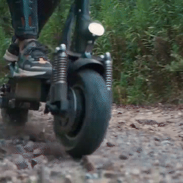 Yume Swift electric scooter riding on rugged terrain with a focus on the front tire and suspension system.